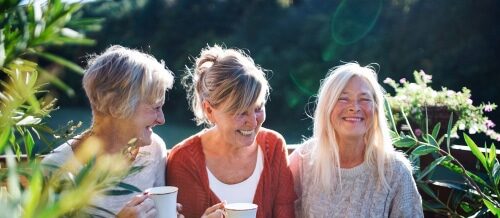 Group of three older women sitting together drinking coffee