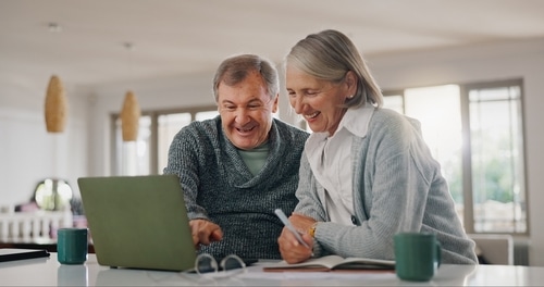 two seniors smiling and looking at computer