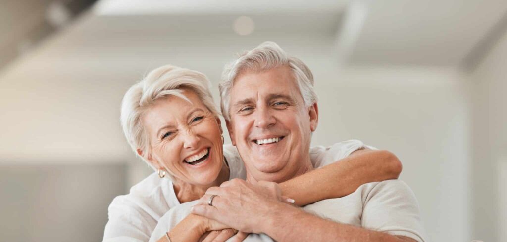 Happy senior couple, portrait and hug on living room sofa for embrace, relationship or love at home. Mature woman hugging man with smile in happiness for care, support or trust together in house